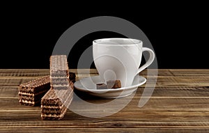 Cup of coffee and waffles on a wooden table isolated on a black