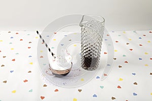 cup of coffee with whipped cream and sprinkles next to a vintage fake crystal decanter