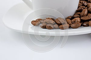 A cup of coffee on a white table. Coffee beans on a saucer close up