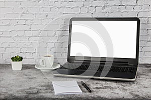 A cup of coffee on a white table with a laptop, notepad and pen. Mock up business concept. Place for your text.