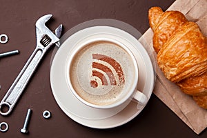 Cup of coffee with WiFi sign on the foam. Free access point to the Internet WiFi. I like coffee break with croissant