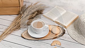 A cup of coffee on wooden slice with cookies and book. Flat lay.