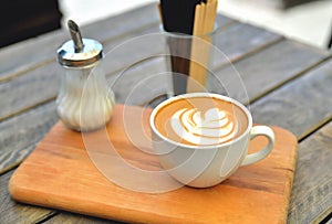 Cup of coffee on a wooden stand is on the table in a cafe summer morning