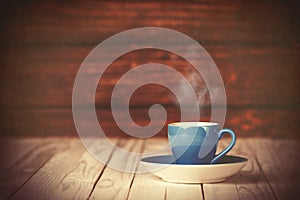 Cup of coffee on wooden table and background.