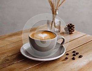 Cup of coffee on wooden table with flower vase and coffee bean decoration