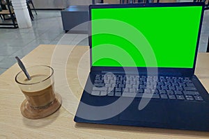 A cup of coffee on wooden table beside laptop