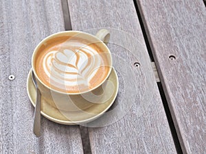 Cup of coffee on the wooden table with latte art.