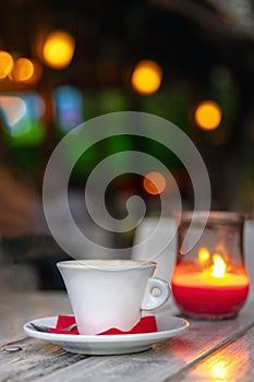 Cup of coffee on a wooden table at night by candle light, outdoors