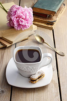 Cup of coffee on wooden table. Vintage books in the background