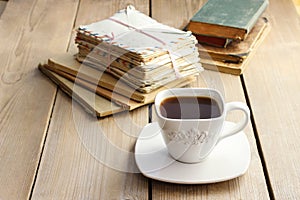 Cup of coffee on wooden table. Vintage books and pile of letters