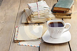 Cup of coffee on wooden table. Vintage books and pile of letters