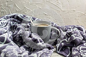 Cup of coffee on a wooden table and a warm plaid. Autumn or Winter concept