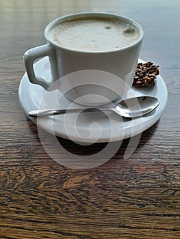Cup of coffee on a wooden table. White cup with saucer and spoon