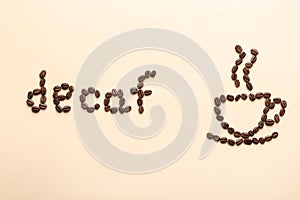 Cup of coffee and word Decaf made with beans on beige background, flat lay