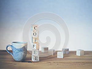 Cup of coffee with word written in wooden blocks