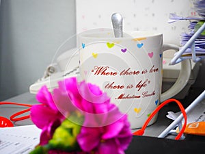 A cup of coffee during work hours with sentence `Where there is love, there is life` photo