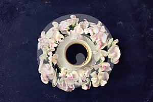Cup of coffee, wreath sweet peas, black shabby table