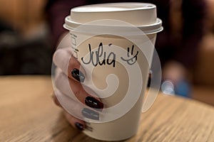 Cup of coffee with writen word JULIA in woman hand