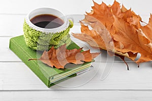 A cup of coffee and yellow leaves and a notebook. The concept of autumn, still life, relaxation, study