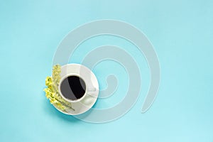 Cup of coffee and yellow wild flowers Linaria, blue paper background Flat lay Top view Concept Good morning or Hello spring Copy