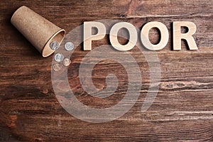 Cup with coins, word POOR and space for text on wooden background