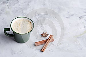 Cup of creamy coffee with cinnamon and star anise on a white textured background, top view, close-up, selective focus