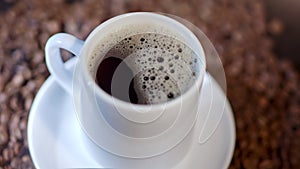 A cup of delicious coffee has been cooked and is served on top of many coffee beans