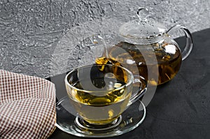 Cup of delicious herbal tea and glass teapot.