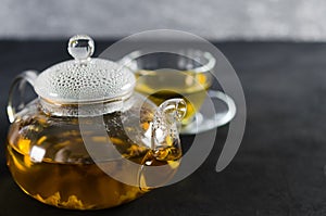 Cup of delicious herbal tea and glass teapot.