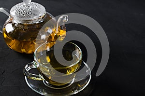 Cup of delicious herbal tea and glass teapot.