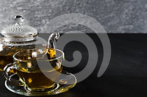 Cup of delicious herbal tea and glass teapot.