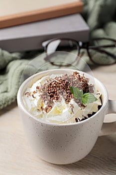Cup of delicious hot chocolate with whipped cream and mint on white wooden table
