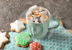 Cup of delicious hot cocoa with marshmallows and Christmas cookies on table