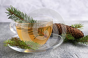 Cup with delicious immunity boosting tea and fir on grey table, closeup