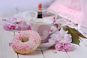 cup with drink coffee cappuccino, hot chocolate with milk, pink donut, lipstick, sakura flowers, caffeine improves functioning of
