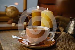 cup with drink coffee on old vintage wooden table, metal coffee maker, candles burn, caffeine improves functioning of human brain