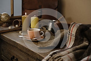 cup with drink coffee on old vintage wooden table, metal coffee maker, candles burn, caffeine improves functioning of human brain