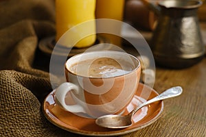 cup with drink coffee on old vintage wooden table, metal coffee maker, candles burn, caffeine improves functioning of human brain