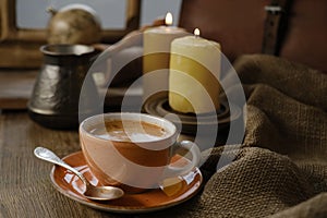cup with drink coffee on old vintage wooden table, metal coffee maker, candles burn, caffeine improves functioning of human brain