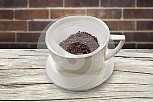 Cup of drip coffee with paper filter tool on wood table and brick wall