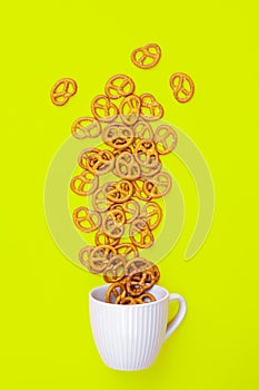 A cup with effuse pretzels on green background, flat lay.