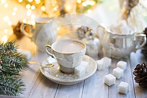 A cup of English tea with milk from an old mother-of-pearl porcelain service with refined sugar. Christmas tea party breakfast on