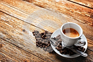 Cup of espresso coffee and beans on an old wooden table