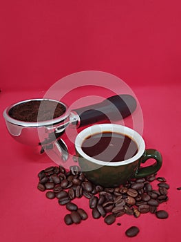 cup of espresso with coffee beans and portafilter filled with grinded coffee