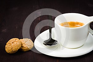Cup of espresso coffee and biscuit near spoon
