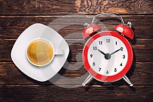 Cup of espresso coffee and vintage clock alarm on wooden table top view
