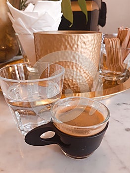 cup of espresso, glass of water, napkins on the table, wooden sticks