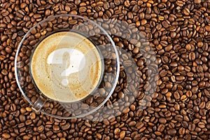 Cup of espresso with question mark on coffee foam on coffee beans background. With copy space