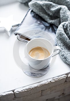 Cup of espresso on white table with cozy interior details