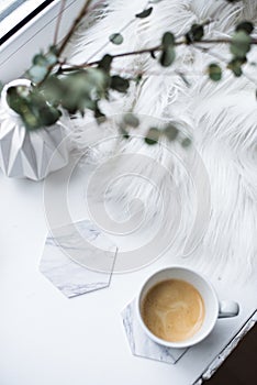 Cup of espresso on white table with cozy interior details